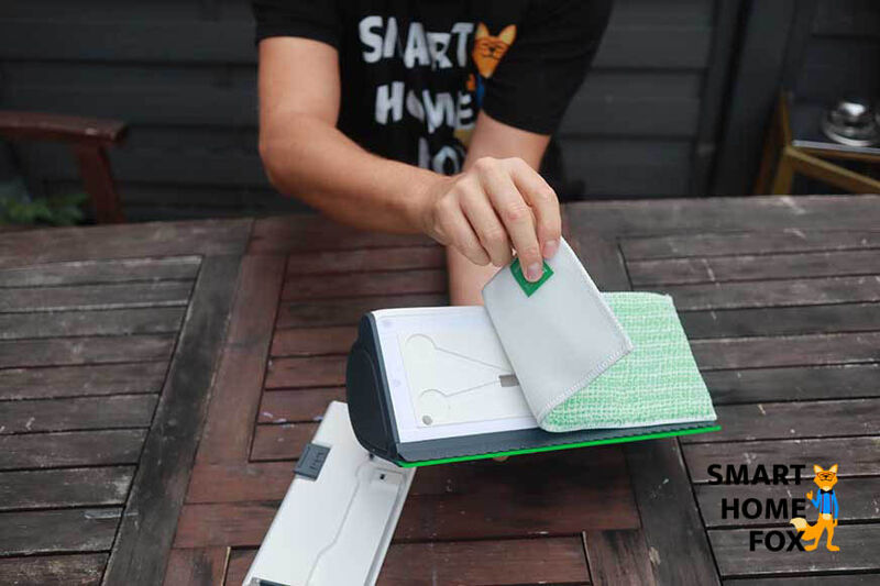 Man sieht, wie das Mikrofasertuch an der Unterseite des Vorwerk Kobold VG100 angebracht wird.